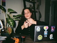 a woman is sitting at a table with a laptop