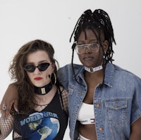 two women wearing glasses and denim posing for a photo